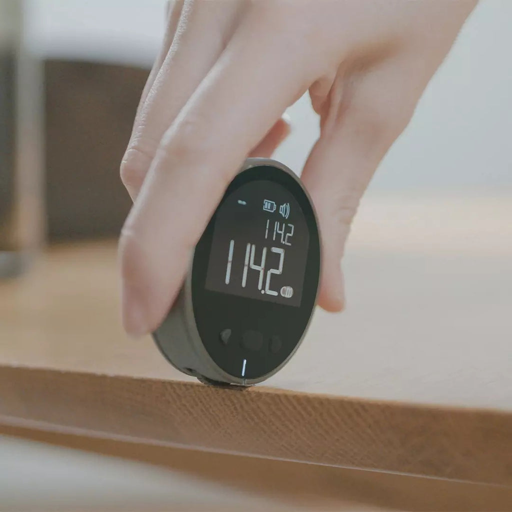Digital thermometer held by a hand with a blurred background